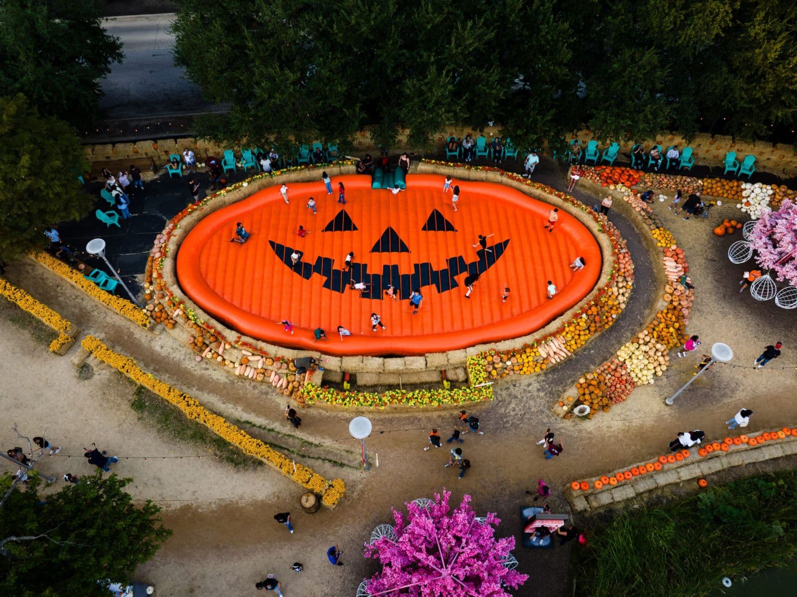 Overhead view of children bouncing on the jack-o'-lantern pillow ringed by pumpkins